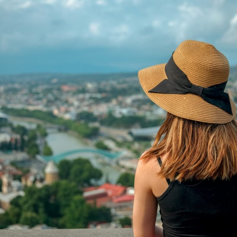 Woman in sun hat looking from panorama at Tbilisi city